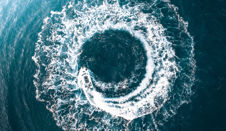 Top-down photo of a motorboat making a ring of power/hurricane shape in the water.